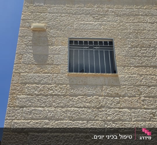 קיר אבן עם חלון סורג בשמש